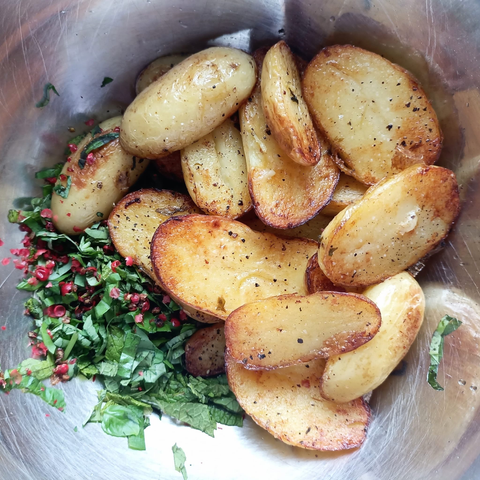 Die gebratenen Kartoffelhälften in einer Schüssel mit Kräutern und Gewürzen.