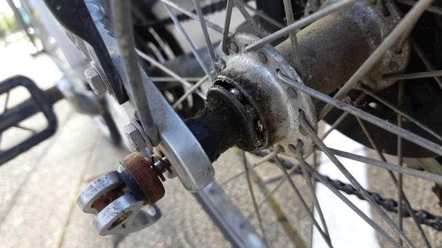 Un moyeu de roue arrière ouvert et en piteux état, qui a déjà perdu quelques billes, sur ce vieux VTC Gitane encore bien poussièreux.