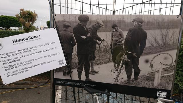 Grande photo titrée « Groupe de cyclistes réparant des vélos, le long du canal du Caen à la mer, vers 1930. Archives du Calvados 2FI/233 ». Et un drapeau surgissant d'un vélo disant : « Hérouelibre :
Permettre les mobilités actives à HSC

• 110 ateliers d'entraide depuis mars 2023 dans  tous les quartiers d'Hérouville
• travaille avec 29 structures normandes dont 14    hérouvillaises
• tou(te)s sont accueilli(e)s et accompagné(e)s à    participer activement
• 22 bulletins d'information mobilité pour les    acteurs de la ville »