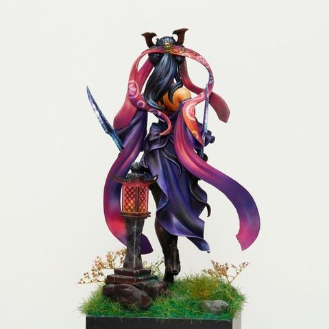 This photo captures the rear view of a meticulously crafted and painted miniature figure, highlighting the dynamic flow and intricate details of the character's attire and environment. The most striking feature in this view is the movement suggested by the long, flowing ribbons. Painted in a gradient of deep crimson to a soft magenta, they create a sense of energy and dynamism, framing the figure and drawing the eye to various elements of the composition. The balance between the ornamental design and the serene yet powerful posture creates a compelling visual narrative.