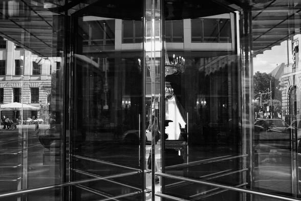 Monochrome photograph of a revolving door in front of an abandoned hotel lobby in Berlin, Germany.