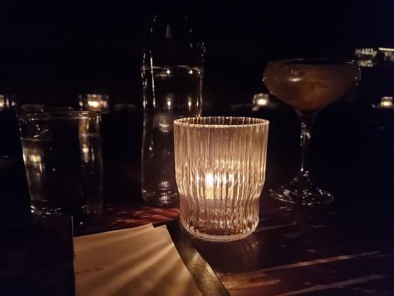Glasses on a table in a restaurant lit by candlelight.