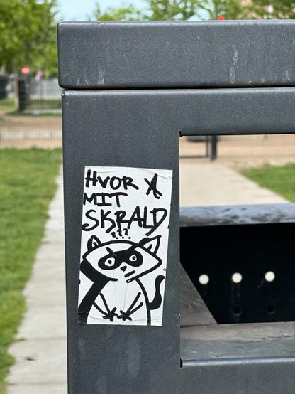a sticker on a bin with a drawing of a raccoon and the text “HVOR A MIT SKRALD?”