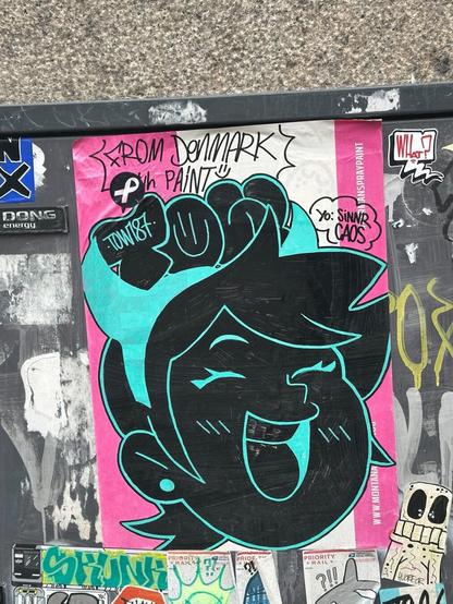a printed sticker with a black and turquoise line drawing, in the shape of a laughing female face in the style of 1950s cartoons, with the letters TOW, in graffiti throw-up style, in its hair