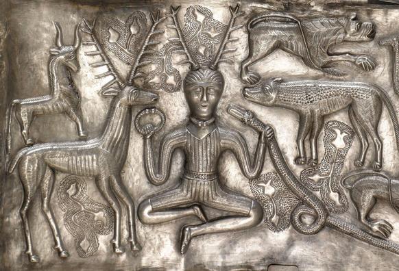 A metal friese depicting several creatires surrounding a horned figure grasping a torc and a snake