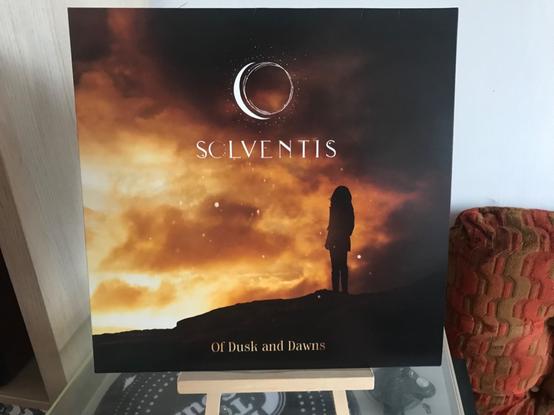 The “Of Dusk and Dawn” vinyl album. On the cover, a woman is set against the light suffusing from twilight clouds.