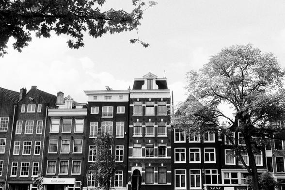 Black and white photo of a row of houses next to a canal in Amsterdam