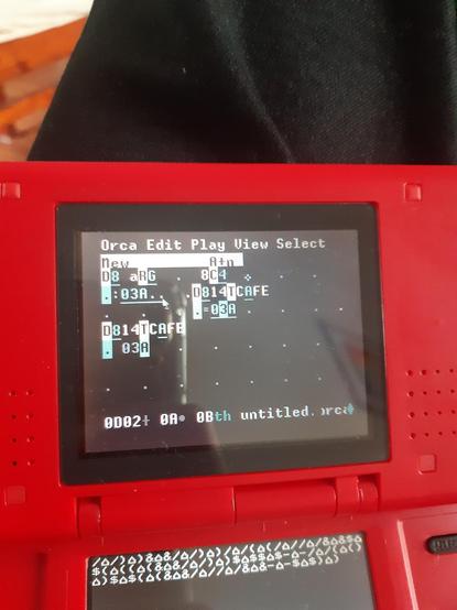 Una foto de una Nintendo DS fat roja, mostrando la máquina virtual uxn con el programa orca.