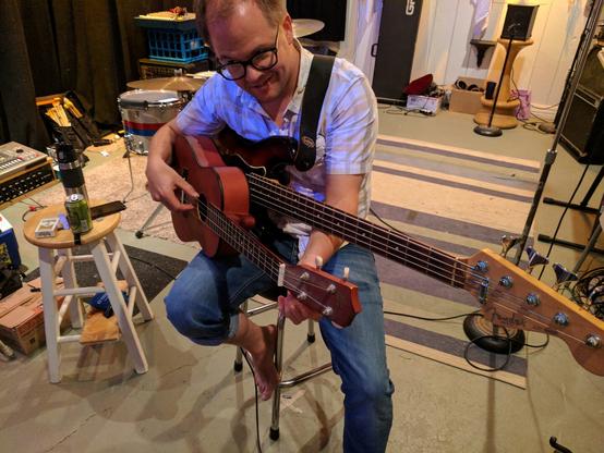 Person sitting with two guitars.