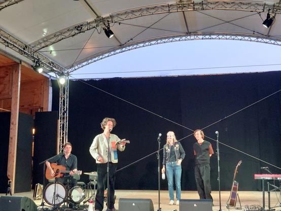 Felix Meyer, Dota Kehr und Max Prosa auf einer Bühne, ein Gitarrist sitzt