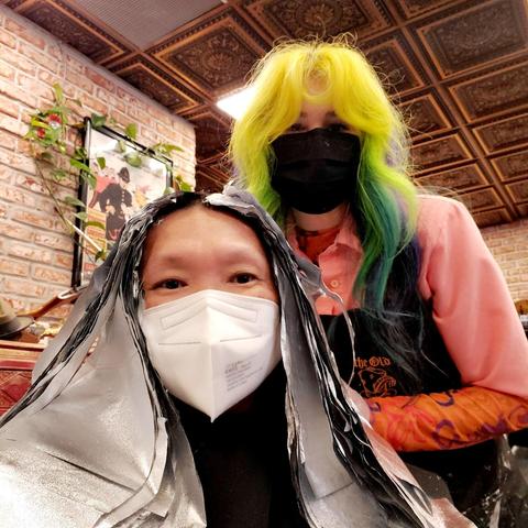 Selfie of me with head covered in hair foils & wearing white face mask, with Garlande, wearing black face mask with yellow & green ombre hair.