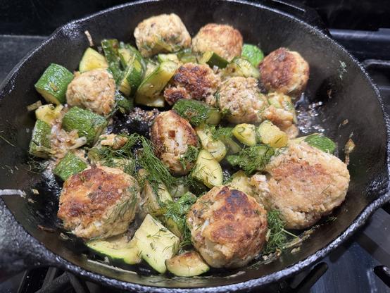 Cast iron pot holding crab balls and diced zucchini.