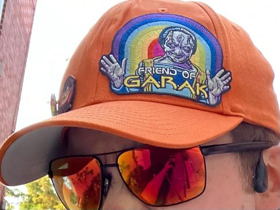 An orange ball cap with a "friend of Garak" rainbow patch on the front
