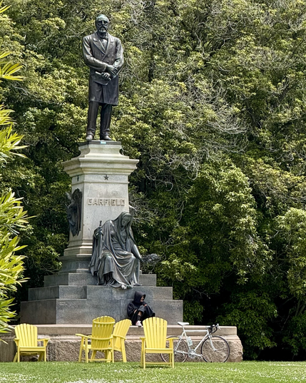 James Garfield, sad woman, person with bike at foot of statute.