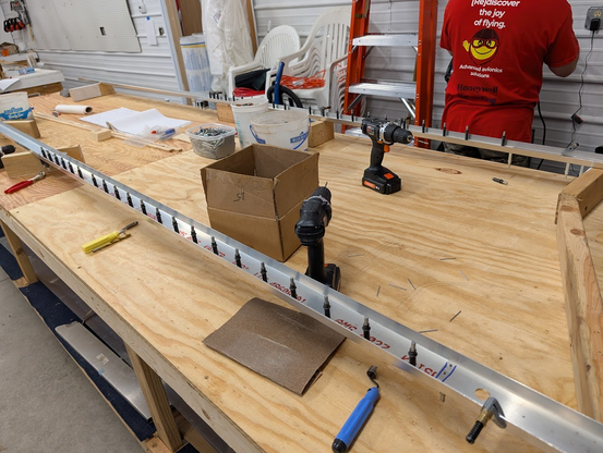 Two rear spars (both wings) on a work bench. Clecos line the spar as holes are being prepared for rivets.
