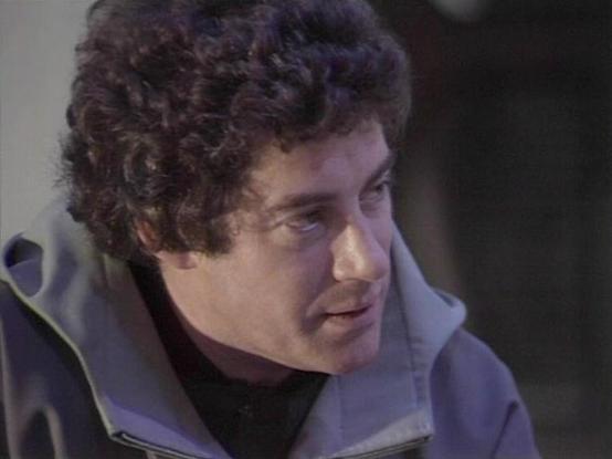 Claude Sonnet 4.0 describes the image as: "I can see this is a scene featuring a man with dark curly hair wearing what appears to be a light-colored, futuristic-style jacket or uniform. The lighting and composition suggest this is from a science fiction television production, likely from the late 1970s or early 1980s based on the visual style and production values. The setting appears to be indoors, possibly on a spacecraft or futuristic facility set. The character appears to be in conversation or delivering dialogue, captured in what looks like a dramatic moment from the series."

Blakes7Bot, version 3.9.30.