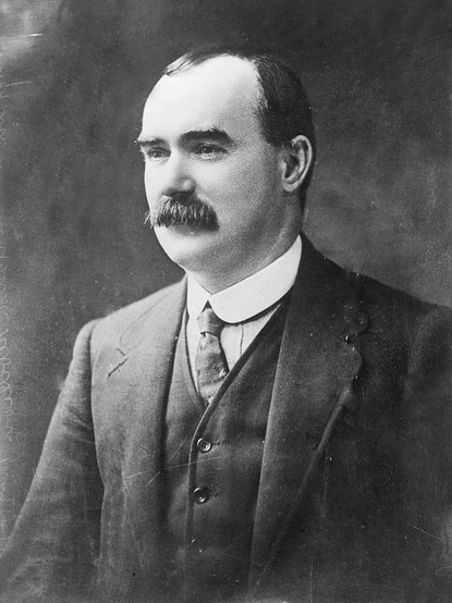 A head and shoulders portrait of James Connolly, Séamas Ó Conghaile, in jacket and tie. He has an extravagant walrus moustache and a receding hairline.