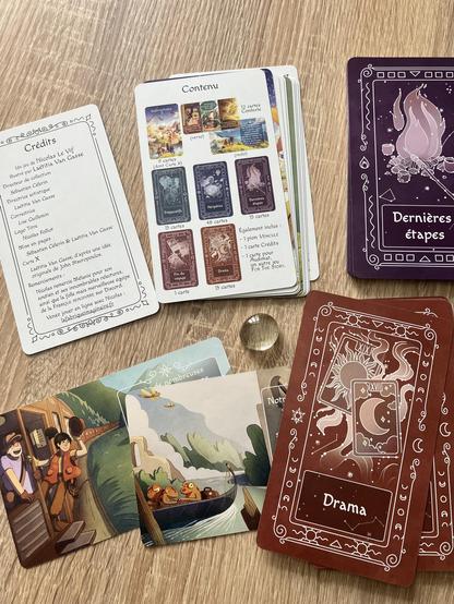 Quelques cartes du jeu étalées, avec une bille plate transparente au milieu.