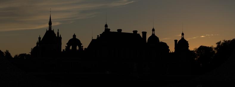 La silhouette du chateau de Chantilly en ombres chinoises sur fond de ciel de soleil couchant