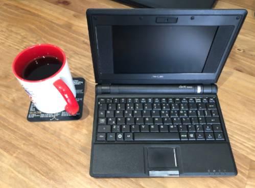 An open eee pc netbook next to a mug of coffee