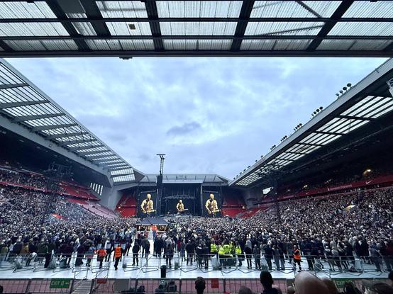 Wide shot of stadium gig with large screens showing Bruce Springsteen playing a guitar.