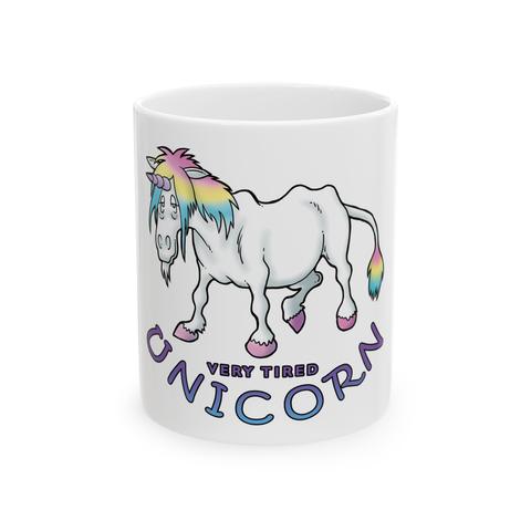 A white coffee mug with a drawing of a very tired-looking, haggard unicorn, white with rainbow mane and tail. The text reads, Very Tired Unicorn.