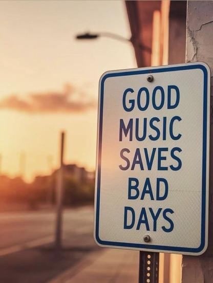A street view with what appears to be a sunset is in the background.  On the bottom right is a sign that reads: "Good music saves bad days."