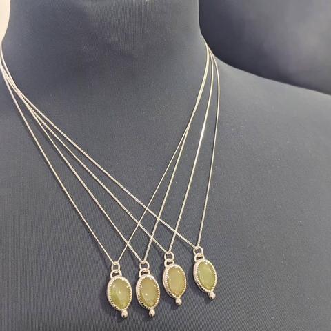 Wider shot of four jade pendants, displayed on a black mannequin