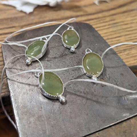 Four jade cabochons placed loosely in their settings. There is dental tape under each stone so it can easily be removed.