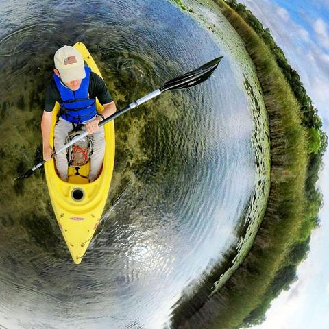 One of a series of photographs in which two people are pictured hiking, biking, and kayaking throughout a beautiful and verdant state park in central Minnesota under cloudy blue late-summer skies.