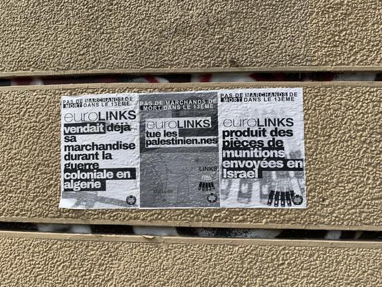 Photo d’un mur dans la rue avec 3 affichettes qui dej nient la vente d’armes par eurolink à Israël