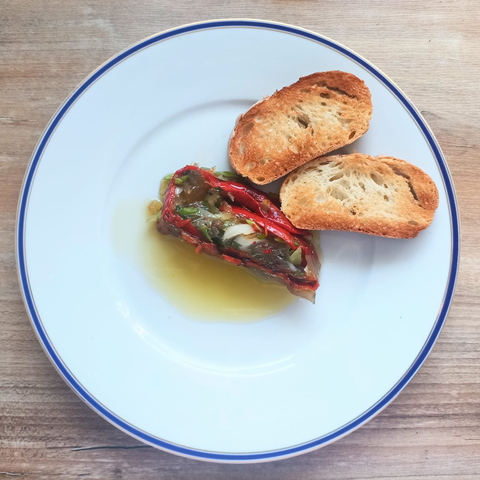 Eine Scheibe der fertigen Terrine auf demTeller mit Olivenöl und Brot