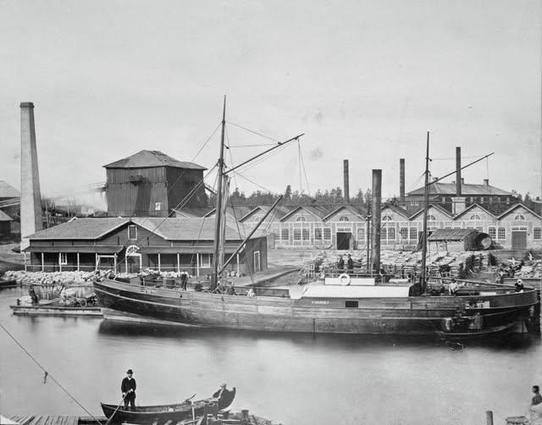 Mustavalkoisessa valokuvassa Oravin ruukki 1870–1880-lukujen asussaan. Etualan höyrylaiva on Motalan konepajalla (Motala Mekaniska Verkstad) vuonna 1867 rakennettu Dagmar, joka liikennöi reitillä Oravi–Viipuri–Pietari. Lähde: Rakennushistorian kuvakokoelma, Museovirasto.