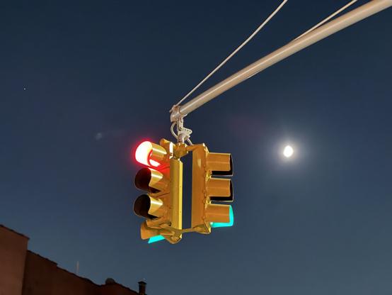 A traffic light showing both red and green colors from two different directions with a night sky in the background.
