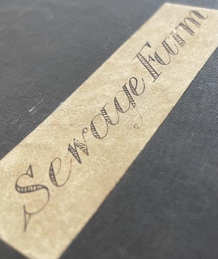 Black cloth book cover with cream label with fancy hand-written title ‘Sewage Farm’.