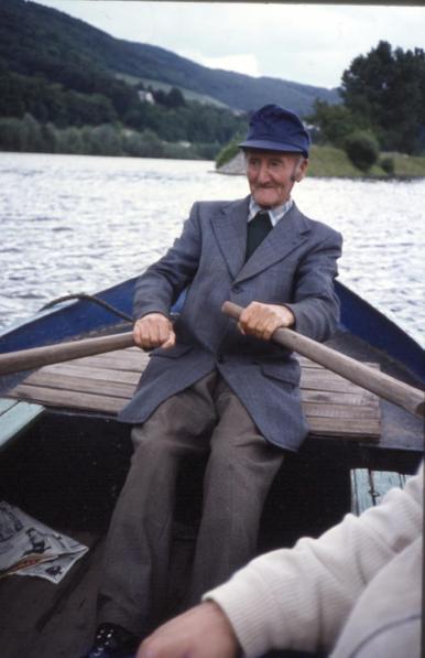 Foto von 1980: Ein Fährmann sitzt im Bug einer Ruderfähre und rudert über die Mosel.