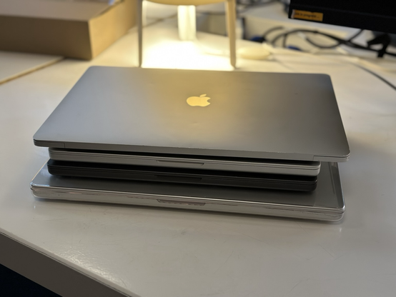 Zwei dünne MacBooks liegen zwischen zwei dicken MacBooks