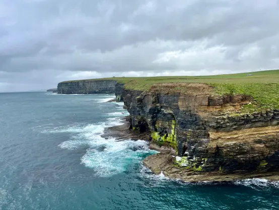Une vue côtière avec des falaises accidentées le long d'une mer turbulente, avec des vagues qui s'écrasent contre les rochers. Nord-ouest des Orcades.