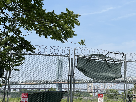 A barbed wire fence with a bridge in the background