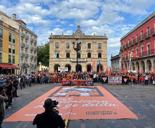 Concentración por las 6 de la suiza en la plaza del ayuntamiento de Xixón con una enorme oancarta solidaria en el suelo.
