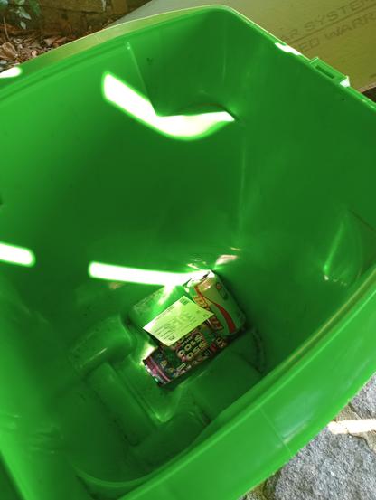 Green plastic bin, with lottery tickets and a can of soda in it
