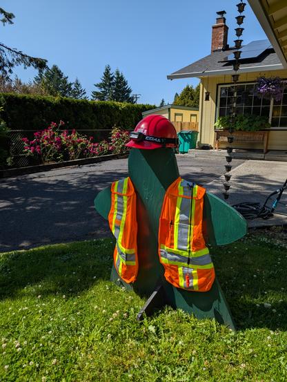 A three-foot plywood meeple wearing a high viz vest and a hard hat.