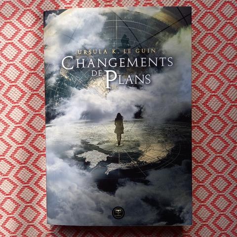 Changements de plans, un recueil de nouvelles d'Ursula K. Le Guin publié aux éditions du Bélial'. La couverture montre une silhouette féminine se tenant au centre d'une carte géante et entourée de nuages