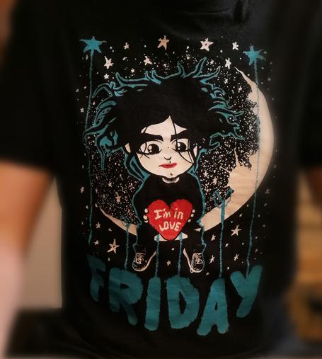 Oberkörperselfie, ich trage ein schwarzes T-Shirt mit dem Aufdruck "Friday" und einer Zeichnung, die dem Cure-Sänger Robert Smith ähnelt, der auf einer Mondsichel sitzt und ein rotes Herz in Händen mit dem Text "I'm In Love" hält.