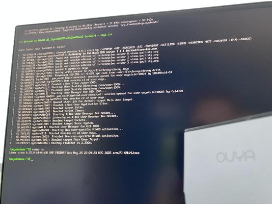 Picture of a monitor and an Ouya console. The monitor shows some logging of NixOS booting up.