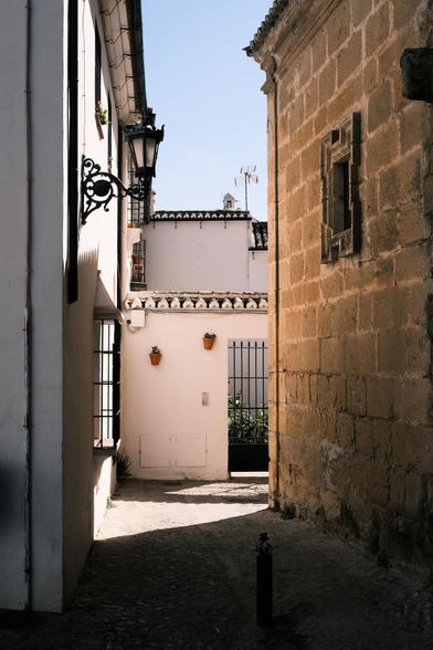 Picture of a small alley in Ronda, partially lighted by the sund while the rest lies in the dark shadows.