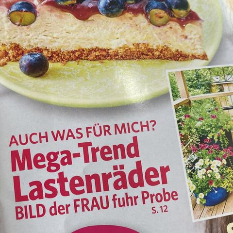 Ausschnitt aus dem Titelbild einer Frauenzeitschrift. Zwischen einem Blaubeerkuchen und einem Gartenfoto steht „AUCH WAS FÜR MICH?
Mega-Trend Lastenräder
BILD der FRAU fuhr Probe“