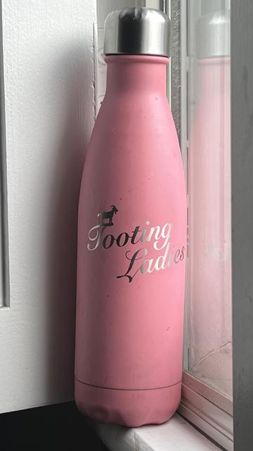Pink water bottle with “tooting ladies” type.