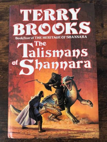a hardback edition of The Talisman of Shannara by Terry Brooks. The cover art depicts a grim reaper-like creature riding a giant lizard and swinging a scythe towards a cloaked man