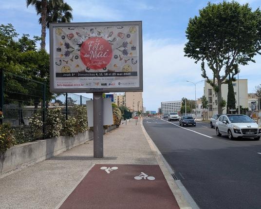 Photo d'une piste cyclable à niveau de trottoir, qui s'interrompt brusquement et sans continuité après un panneau publicitaire.